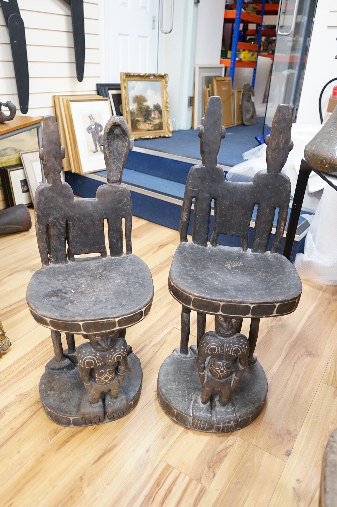 Papua New Guinea Sepik River, a near pair of ‘ceremonial’ figural chairs, each carved from a single section of a tree trunk with integral male and female backs and an castor figure front support with cowrie shell eyes. H